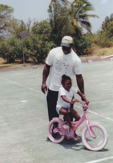 A dad helping his daughter learn how to ride her bike in St. Maarten. 