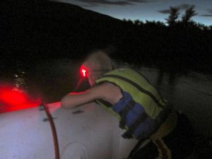 Eddie leans over the side of the boat in the dark. 