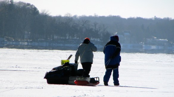 ice fishermen dragging sleds