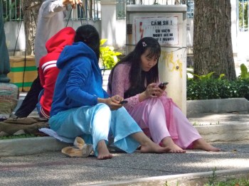 women in ao dais sitting on curb